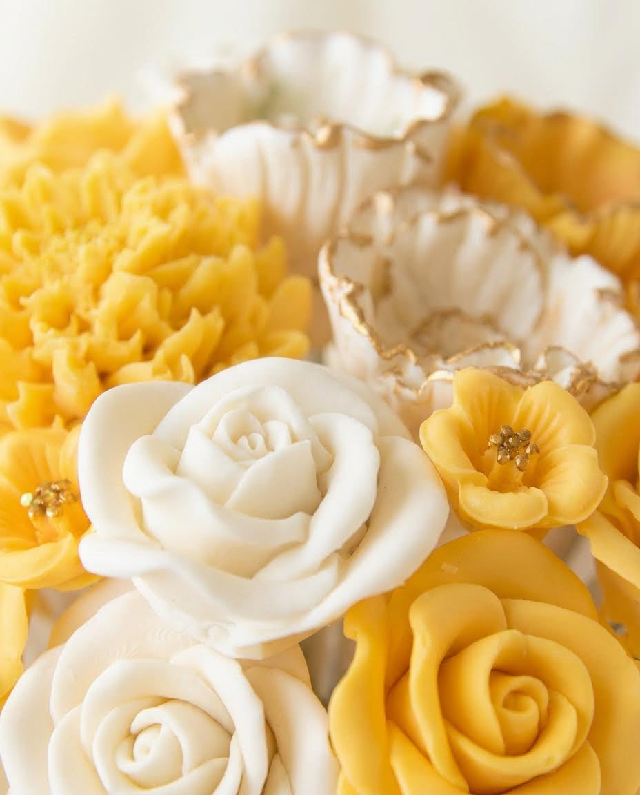 Close-up of yellow and white 3D chocolate flowers with gold accents.